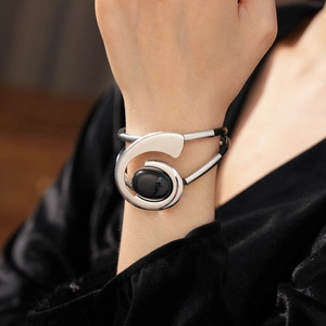Detail of silver wrap bracelet featuring a black oval gemstone on woman's wrist