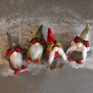 Set of four plush Christmas gnomes with tall hats and white beards on artificial snow