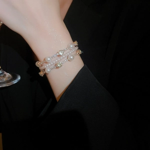 Detail of multi-layer pearl bracelet with sparkling rhinestones on black suit sleeve