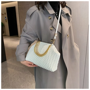 Modern white pleated evening bag with gold chain shown on a grey trench coat