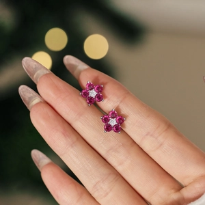 Détail des boucles d'oreilles en argent sterling fleur de prunier avec gemmes roses sur doigt