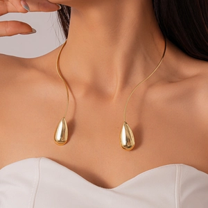 Gros plan d'un collier rigide doré en forme de goutte avec finition miroir sur mannequin