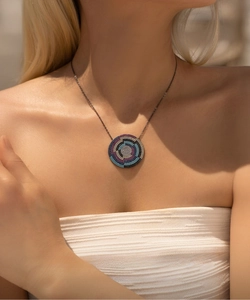 Detail of pixel style shield necklace with colorful micro-pave stones on dark gunmetal chain