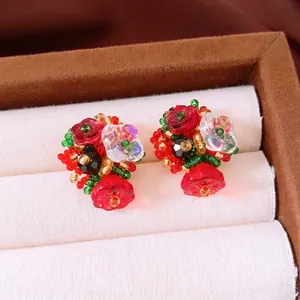Vintage handmade floral beaded earrings with red and green glass beads on white velvet