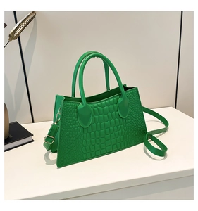 Close-up of vibrant green faux crocodile textured handbag with elegant gold hardware