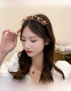 Detail of Happy Birthday headband with pink rhinestones worn by a model in a warm setting