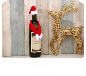 Détail du décor de bouteille de Noël avec mini bonnet de Noël et écharpe rouge