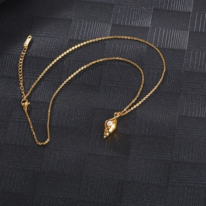 Detailed view of a golden conch pendant with a white pearl on a titanium steel necklace