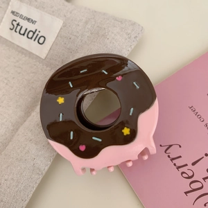Close-up of chocolate and pink donut hair claw clip with colorful sprinkles and heart icons