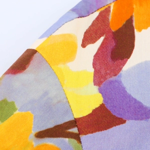Gros plan d'un tissu floral abstrait avec détails de coutures jaunes et bordeaux