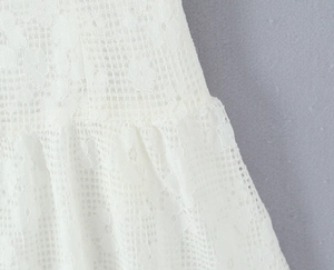 Détail du tissu en maille de dentelle blanche avec motifs ajourés sur une robe d'été