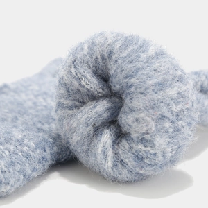 Close-up of a fluffy deep blue faux fur pompom on a thick winter knitted hat