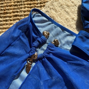 Détail du tissu en maille bleu roi avec boucle en métal doré gaufré sur un bikini