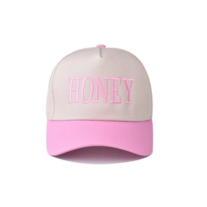 Close-up of pink 'HONEY' embroidery on beige cotton baseball cap with structured panels