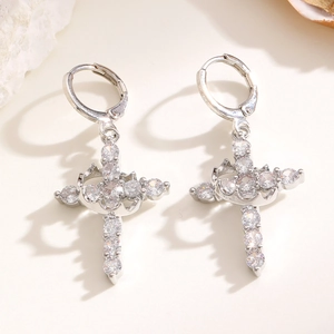 Detailed macro view of silver cross earrings with sparkling cubic zirconia on a white base