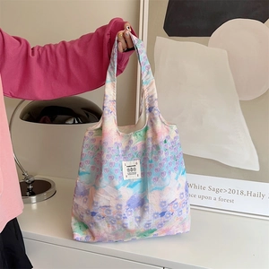 Borsa tote in tela con motivi floreali pastello portata da una modella in una stanza