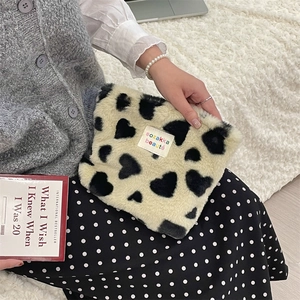 Close-up of heart pattern plush cosmetic bag held with elegant pearl accessories