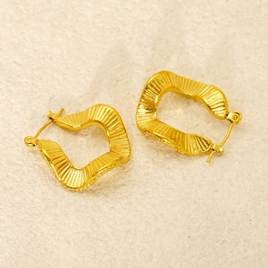 Detailed close-up of gold irregular square earrings with pleated metal texture on stone