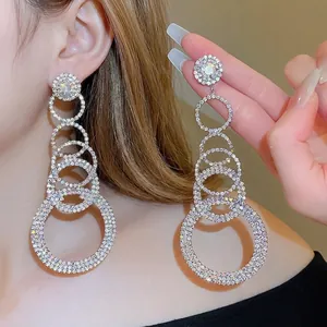 Dramatic layered silver hoop tassel earrings with shimmering rhinestones on a model