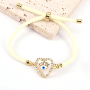 Detailed macro view of yellow braided rope bracelet with heart shaped evil eye charm