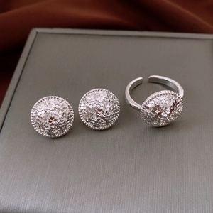 Vue macro de boucles d'oreilles plissées argentées et d'une bague ouverte assortie