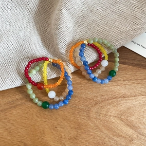 Detail view of handmade colorful stone bead rings featuring diverse floral patterns and textures