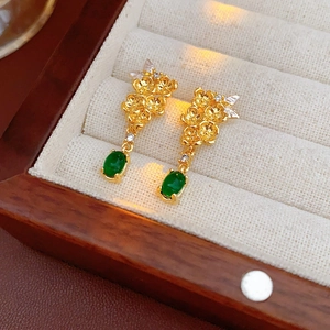 Détail de boucles d'oreilles fleur dorées avec jade vert et diamants dans un coffret à bijoux