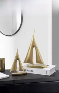 Nahaufnahme goldener abstrakter Segelboot-Skulpturen auf schwarzem Tisch als Büro-Deko