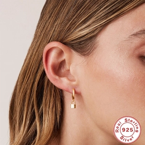 Gold S925 sterling silver octagonal star and lock drop earrings worn by a model