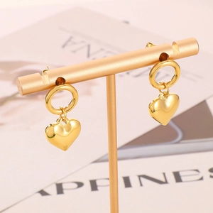 Detailed close-up of golden stainless steel hoop earrings with 3D heart pendants