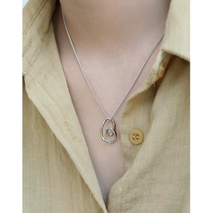Minimalist S925 silver necklace with irregular heart pendant on a yellow linen shirt