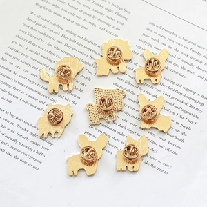 Set of eight gold enamel Corgi pins with butterfly clasps on vintage book page
