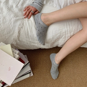 Gray low-cut invisible socks with black polka dot pattern shown in a home setting