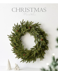 Close-up of a festive Christmas wreath with pine cones against a minimalist white wall