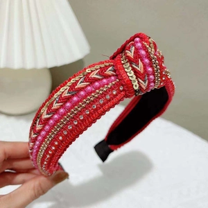 Detailed view of red knotted headband featuring intricate pink pearls and sequins