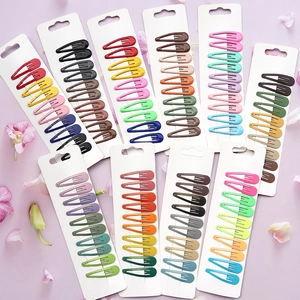 Flat lay of colorful matte metal snap hair clips set on pink floral background