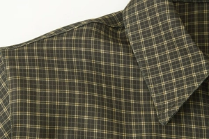Detailed macro view showing the classic collar and olive green plaid cotton fabric texture