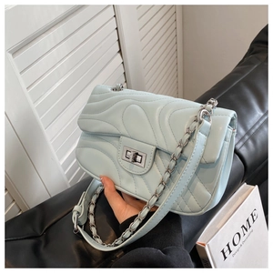 Detail of light blue quilted crossbody bag showing chain strap and silver twist lock