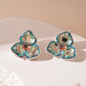 Macro detail of vintage floral crystal earrings featuring teal petals and champagne center