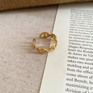 Detailed macro view of a gold-plated Chaine d'Ancre style open ring on beige textured fabric