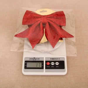 Red glitter Christmas bow decoration on electronic scale showing weight of 17 grams