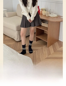 Close-up of Japanese style black crew socks with white stripes on a grey pleated skirt