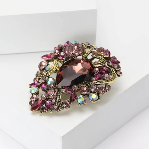 Detailed macro view of vintage rhinestone brooch with red teardrop gem and gold filigree