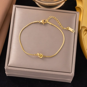Close-up of gold stainless steel snake chain bracelet featuring a minimalist knot detail