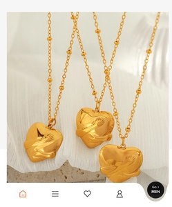 Close-up of three 18K gold-plated heart hug pendants on a beaded chain necklace