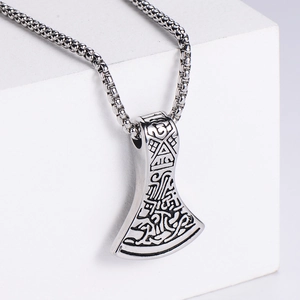 Detailed close-up of a silver Viking axe pendant featuring intricate Nordic carvings and texture