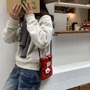 Detail of red plush crossbody bag with white flower decoration on a fashion model