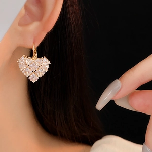 Gros plan de boucles d'oreilles cœur dorées avec oxydes de zirconium sur modèle