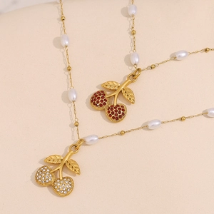 Detailed view of cherry pendant necklaces with red and white gems and gold plating
