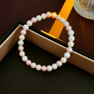 Close-up of white and champagne pearl bracelet on a luxury black jewelry box with warm light